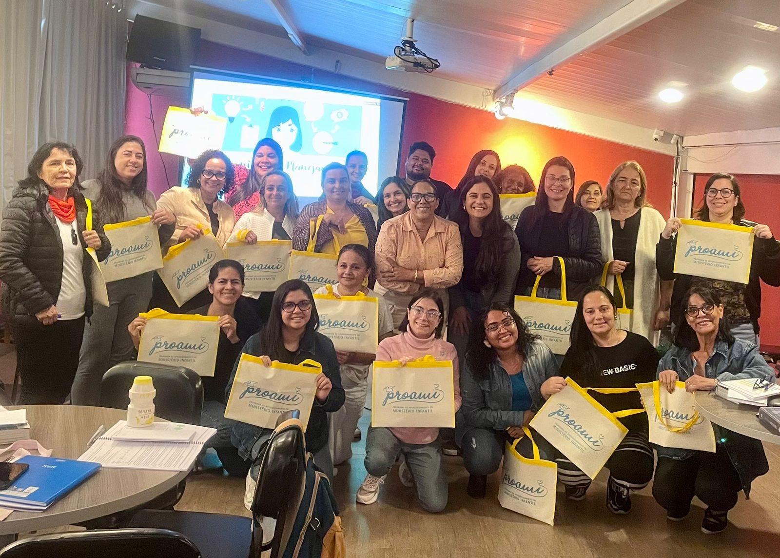 Turma presencial do Proami reunida sorrindo com sacolas personalizadas Proami