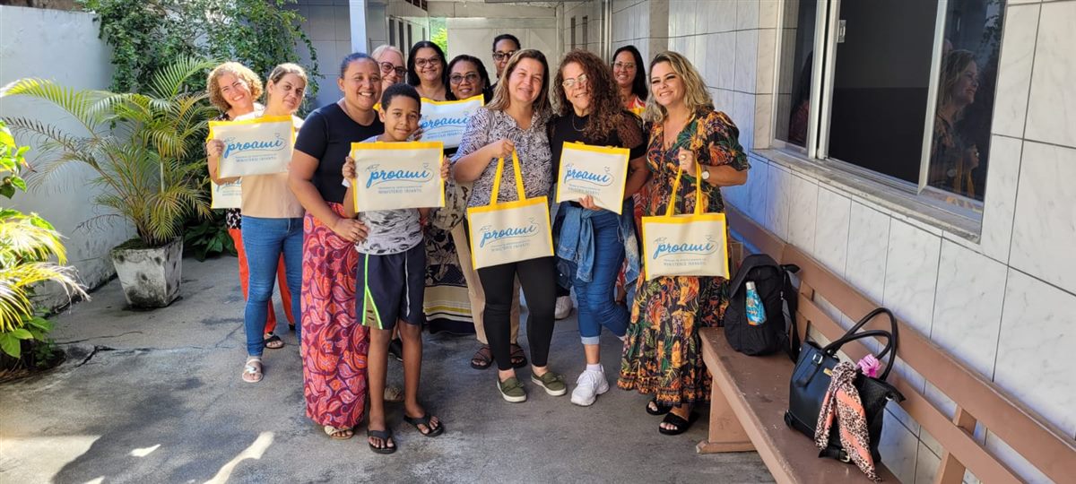 Alunos do Proami reunidos no quintal segurando sacolas personalizadas
